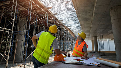 Engineer discussing with foreman about project in building construction site. Engineer and Architect working at Construction Site with blue print